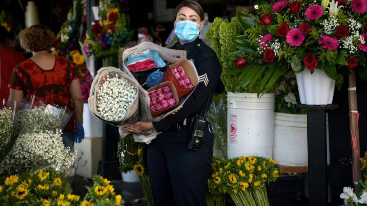 Une policière portant un masque de protection contre le nouveau coronavirus achète des fleurs à Los Angeles, le 8 mai 2020.
