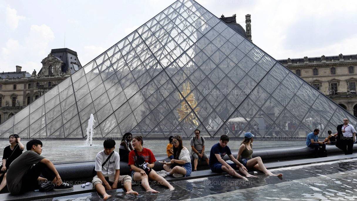 En pleine canicule, des touristes tentent de se rafraîchir près du musée du Louvre, à Paris. 
