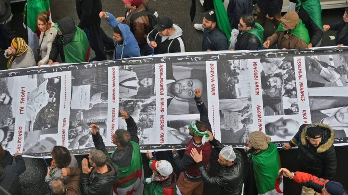 Des manifestants algériens défilent dans les rues de la capitale Alger en portant une bannière où figurent les portraits de militants incarcérés, le 15 novembre 2019.
