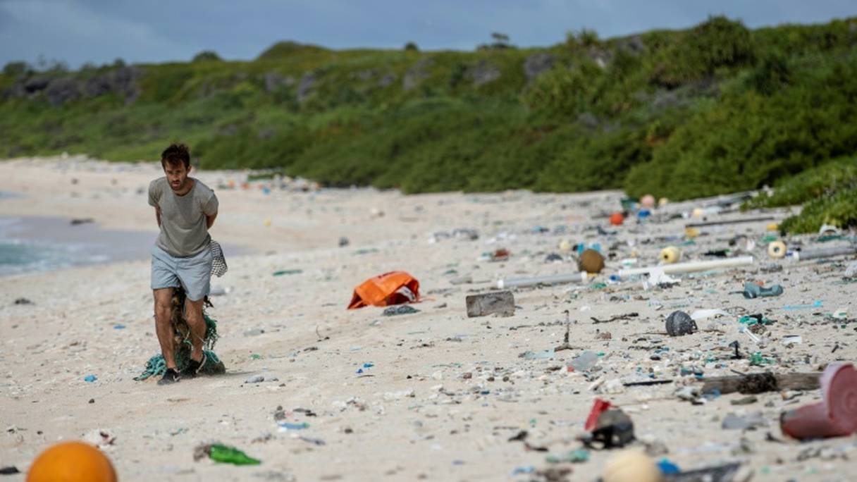 Un homme tente de nettoyer une plage de l'île Henderson dans le Pacifique, le 14 juillet 2019. 
