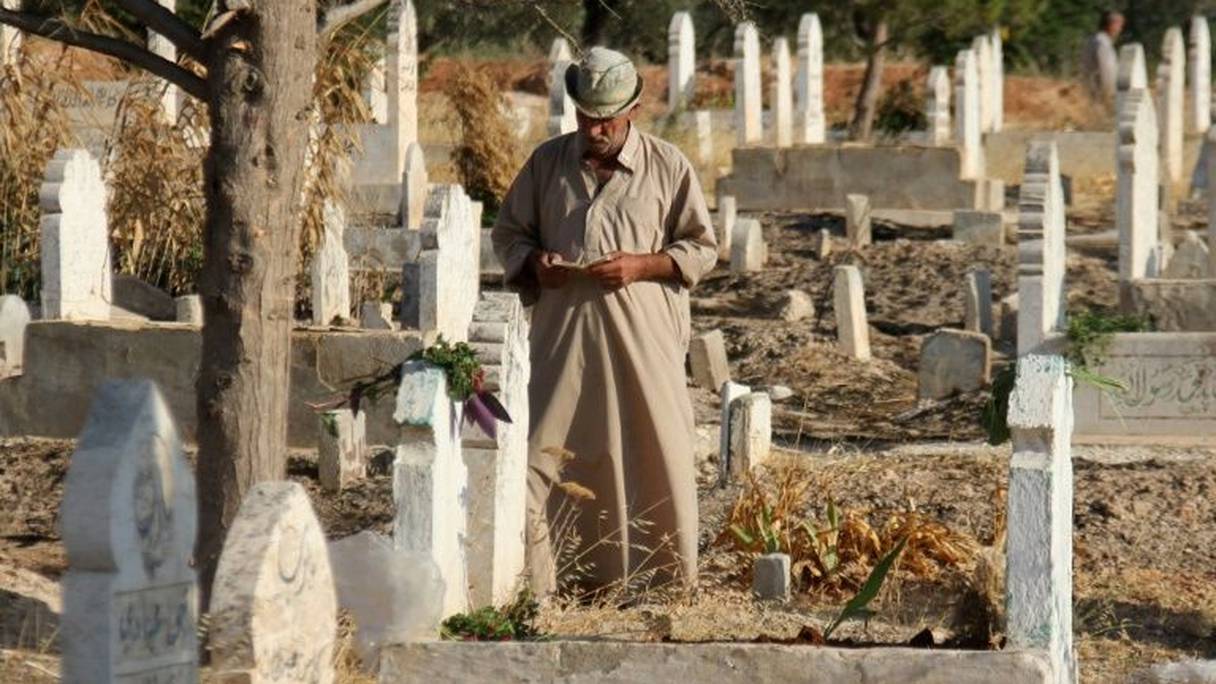 Un Syrien lit le coran sur les tombes de proches et de membres de sa famille au premier jour de l'Aïd al-Adha, le 1er septembre 2017 à Binnish.
