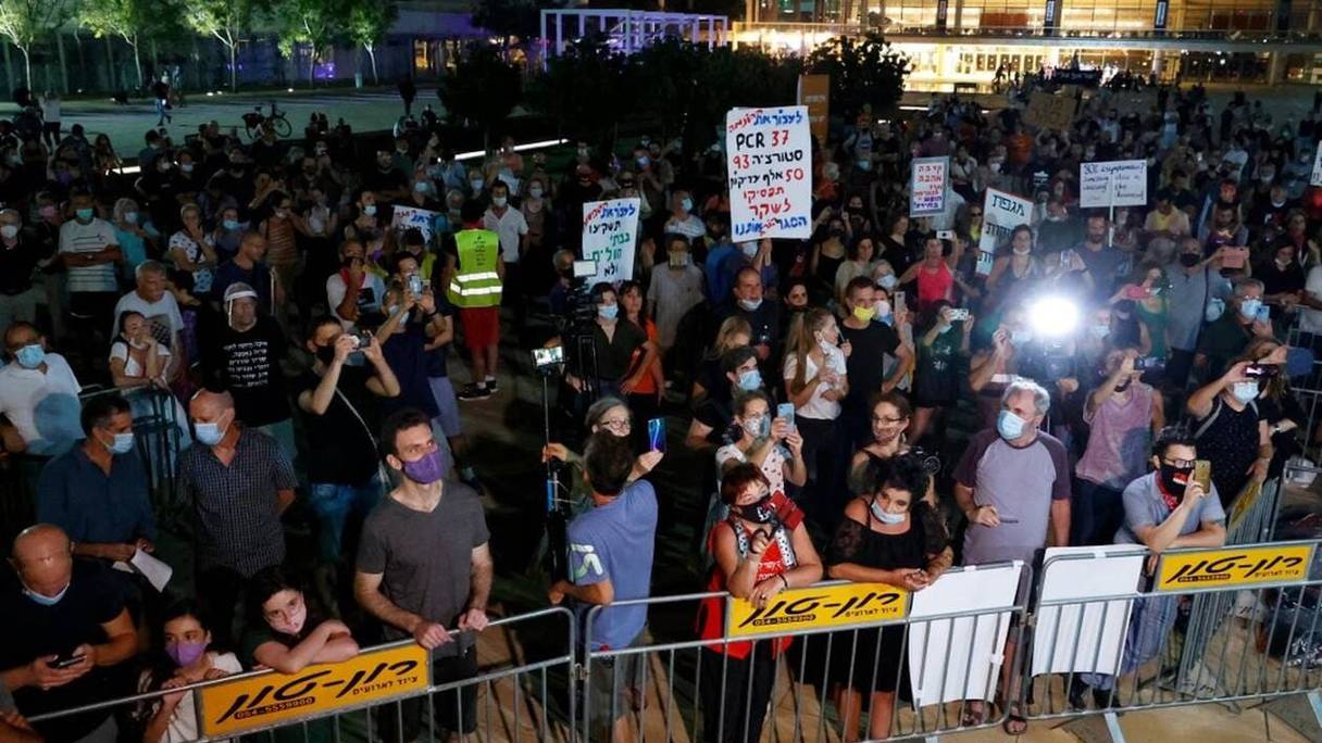 Des manifestants masqués protestent contre la nouvelle mesure de confinement annoncée en Israël, à Tel Aviv, jeudi 17 septembre 2020 en soirée. 
