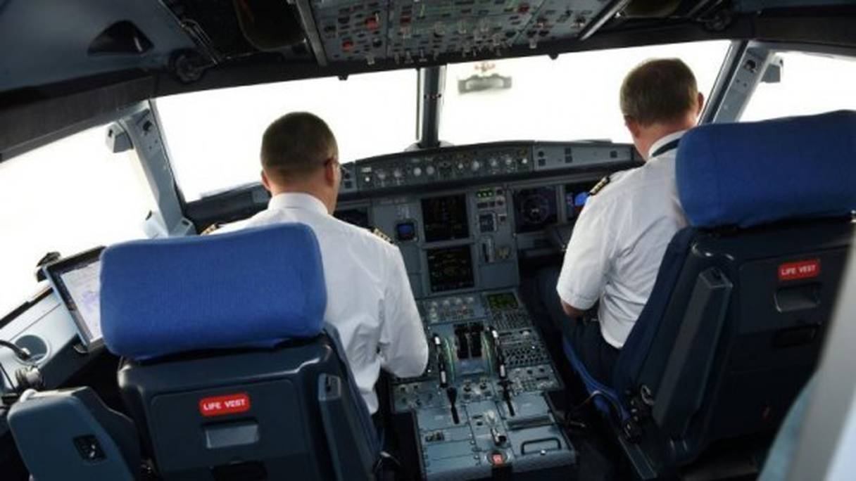 Un pilote et un co-pilote, à l'intérieur du cockpit d'un avion de ligne. 
