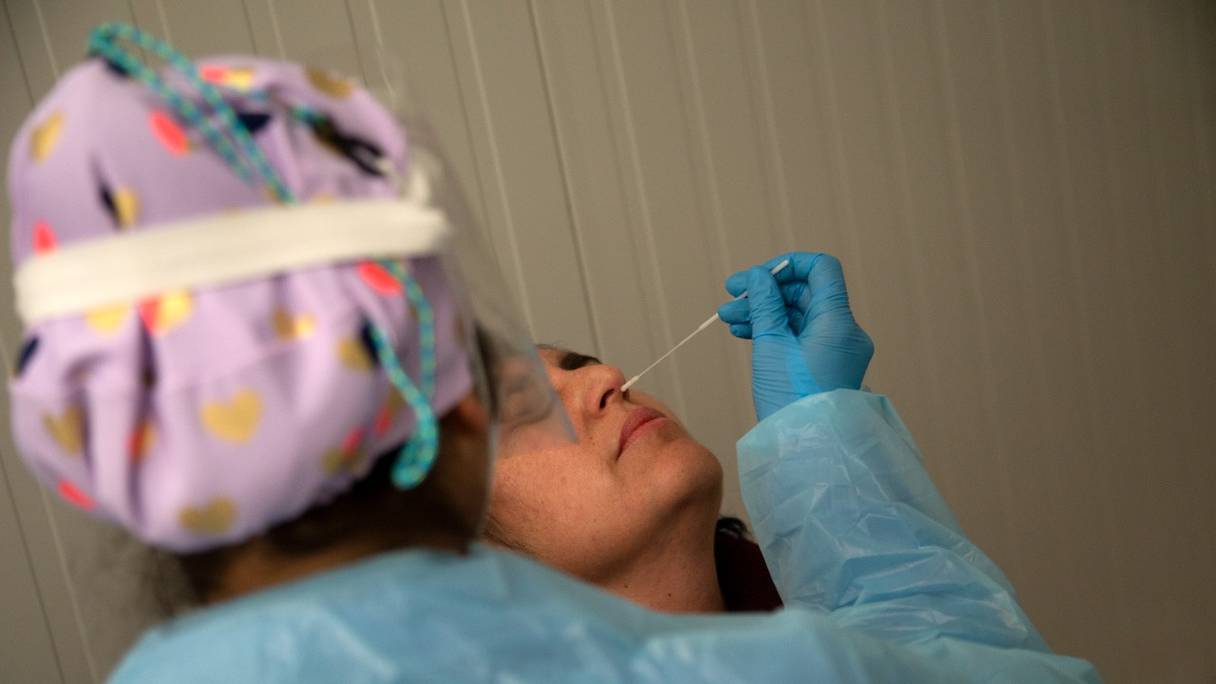 Un agent de santé portant un équipement de protection prélève un écouvillon nasal pour les besoins d'un test PCR Covid-19, ici à Santiago du Chili, le 26 août 2021.
