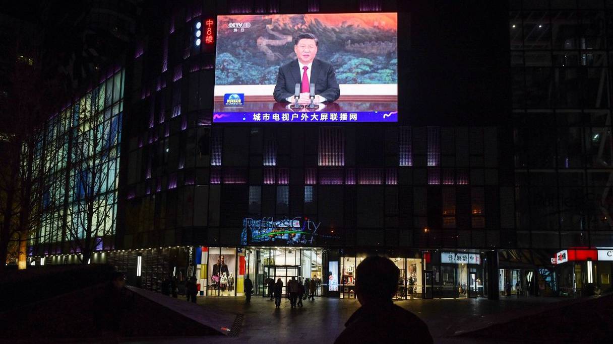 Des personnes passent devant un centre commercial à Pékin, où un écran géant diffuse l'intervention du president chinois Xi Jinping en visioconférence lors du sommet de l'APEC en Malaisie, le 19 novembre 2020.
