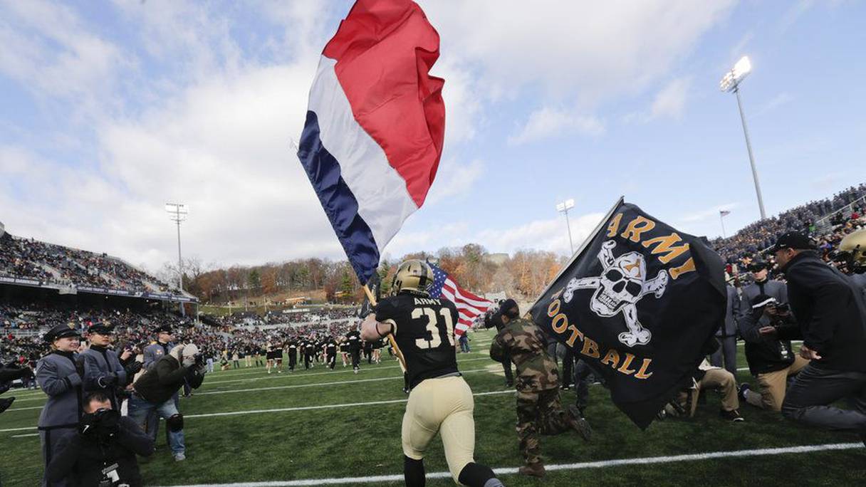 Caleb McNeill porte un drapeau français lors de son entrée sur le terrain avant un match de football américain (NCAA).
