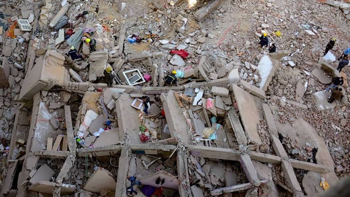 Des personnes et des sauveteurs se rassemblent autour des décombres d'un bâtiment qui s'est effondré dans le quartier populaire de Gesr Giza, à l'est de la capitale égyptienne, Le Caire, le 27 mars 2021.
