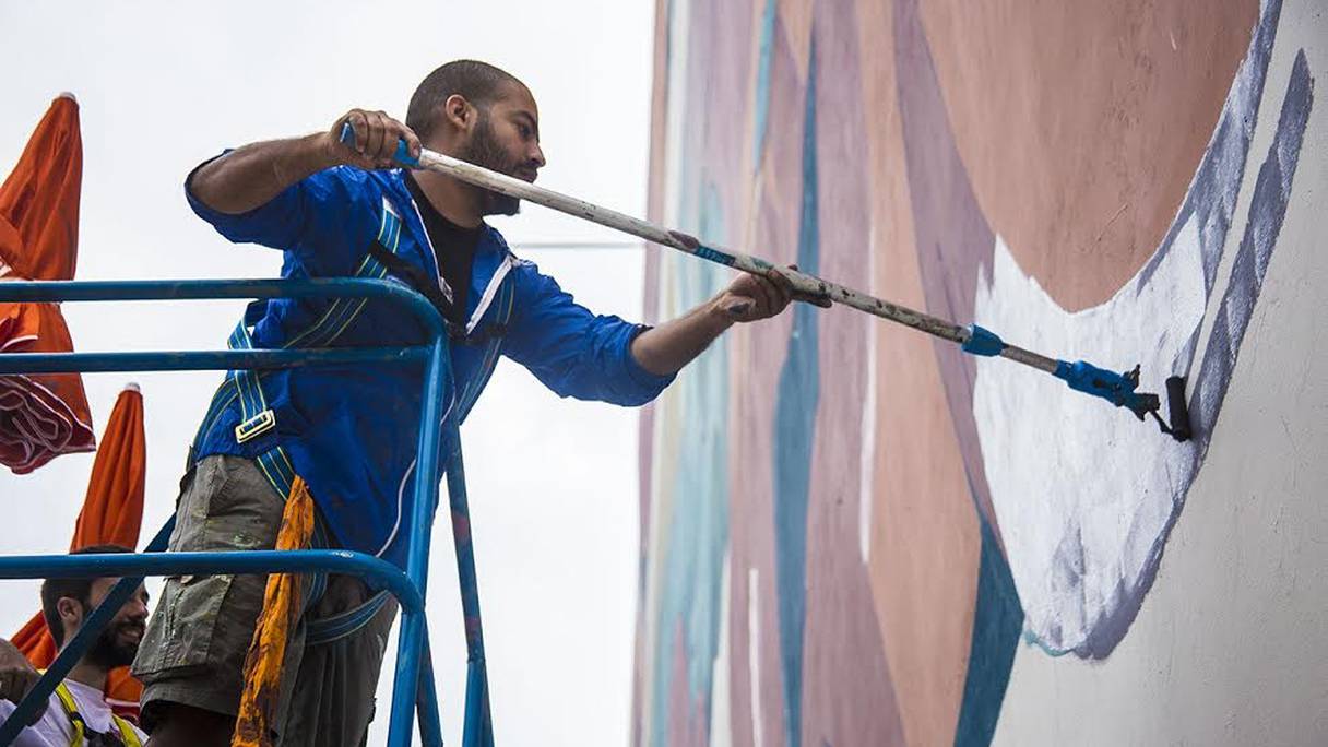 Un artiste en pleine réalisation d'une fresque murale pendant le festival JIDAR, à Rabat.
