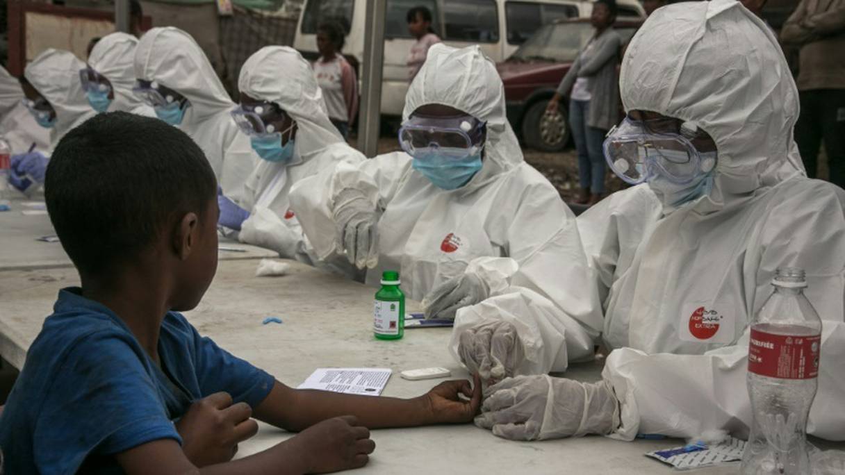 Des agents de santé prélèvent des échantillons de sang d'un enfant pour détecter le coronavirus, à Antananarivo le 3 avril 2020.
