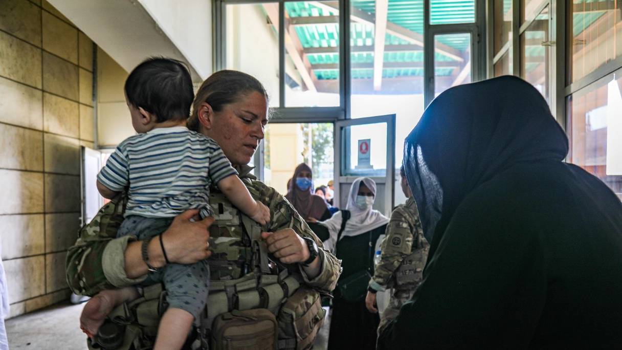 Un médecin de l'armée américaine aide une Afghane avec son enfant lors de l'évacuation en cours des non-combattants du personnel civil américain, de demandeurs de visa d'immigrant spécial, depuis l'aéroport international Hamid Karzai de Kaboul, le 25 août 2021.
