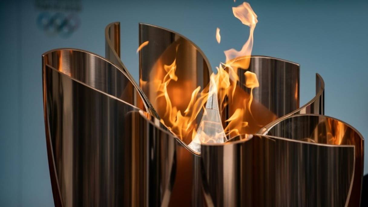 La flamme olympique devant un logo des JO-2020 lors de son arrivée à la gare ferroviaire de Fukushima le 24 mars 2020.
