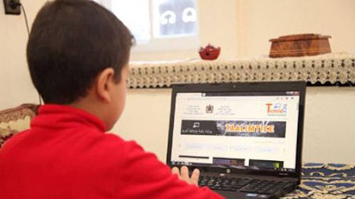 Un élève suit un cours à distance, à partir de son ordinateur à la maison.
