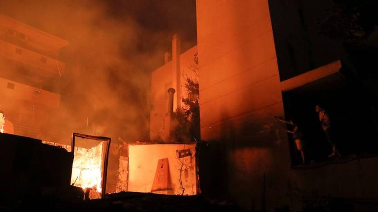 Des habitants tentent d'éteindre une maison en flammes à Mati.
