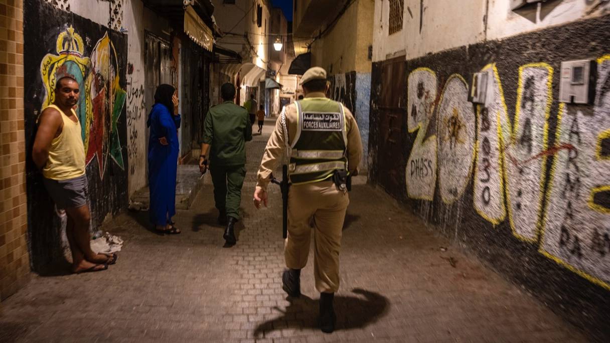 Des agents d'autorité, accompagnés d'éléments de la force publique, patrouillent à la vieille médina de Rabat, le 3 août 2021
