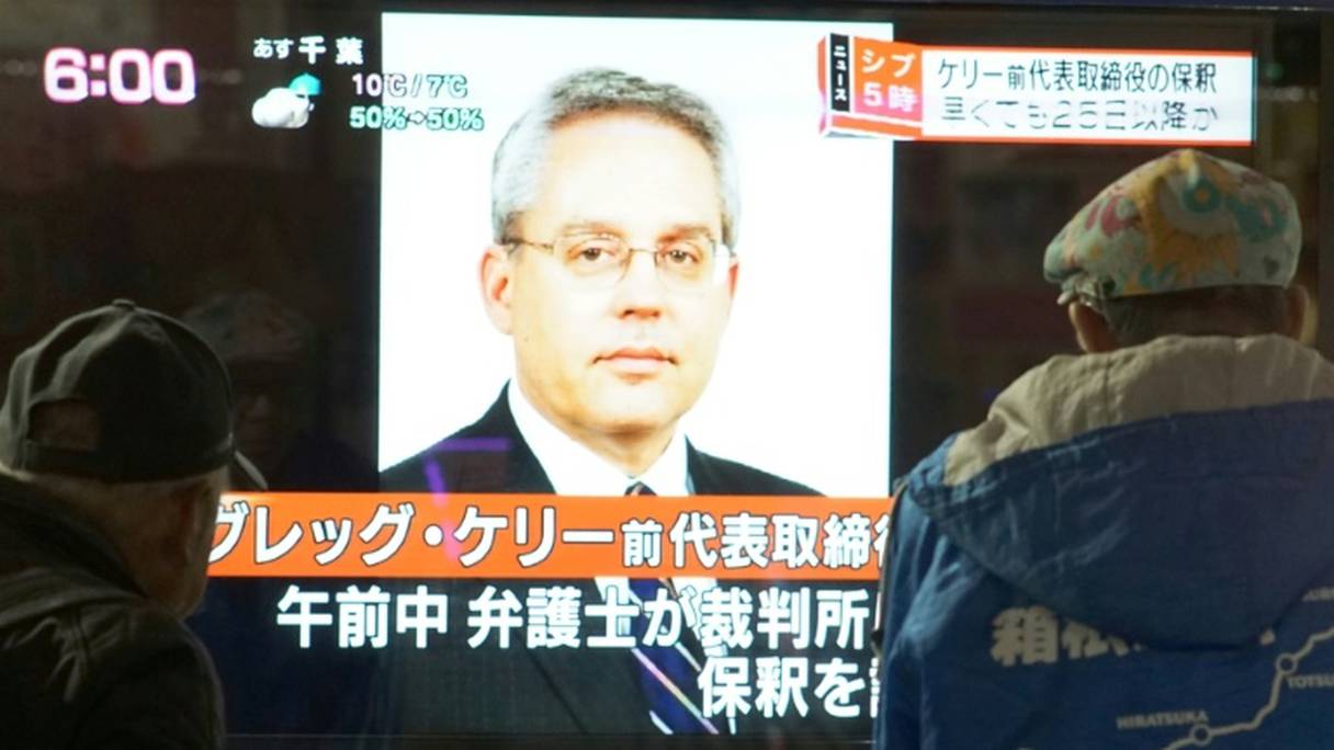 Des piétons passent devant un écran de télévision sur lequel apparaît le visage de de Greg Kelly, ancien bras droit de Carlos Ghosn, le 21 décembre 2018 à Tokyo.
