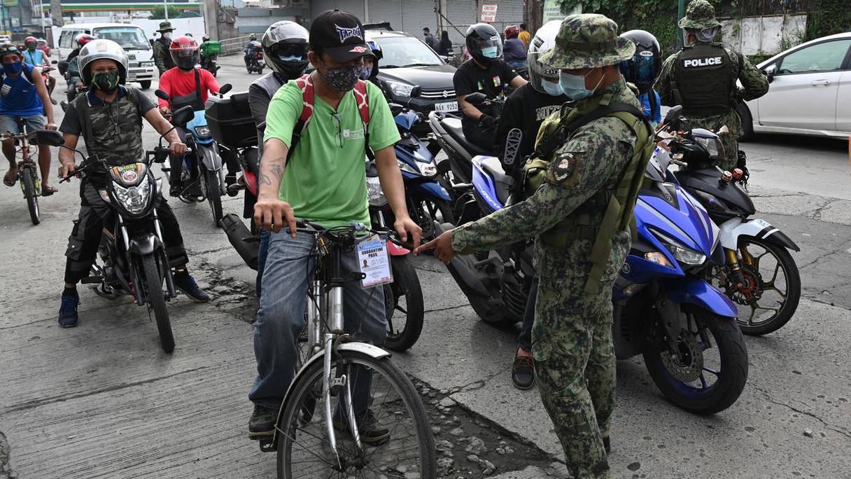 La police vérifie l'identité des motocyclistes, alors qu'un reconfinement est mis en place à Manille, la capitale, le 4 août 2020. 
