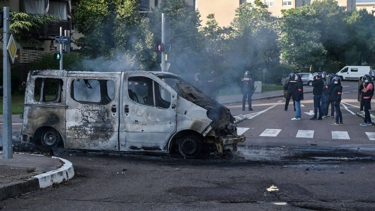Des policiers et des gendarmes à proximité d'une camionnette brûlée dans le quartier des Grésilles, à Dijon, le 15 juin 2020.
