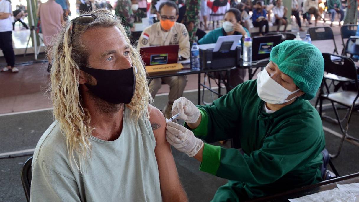 Un homme étranger reçoit le vaccin contre le coronavirus d'AstraZeneca dans une clinique de vaccination de fortune à Denpasar, dans l'île indonésienne de Bali, le 5 juillet 2021, alors que la nation d'Asie du Sud-Est lutte contre une vague sans précédent de nouvelles infections.
