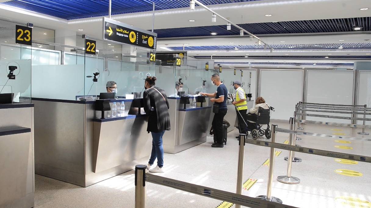 Un policier contrôle les documents sanitaires de voyageurs à l'aéroport Mohammed V de Casablanca, le 4 septembre 2021. Les autorités marocaines ont décidé d'intensifier leurs contrôles pour lutter contre les tests PCR et les pass vaccinaux falsifiés. 
