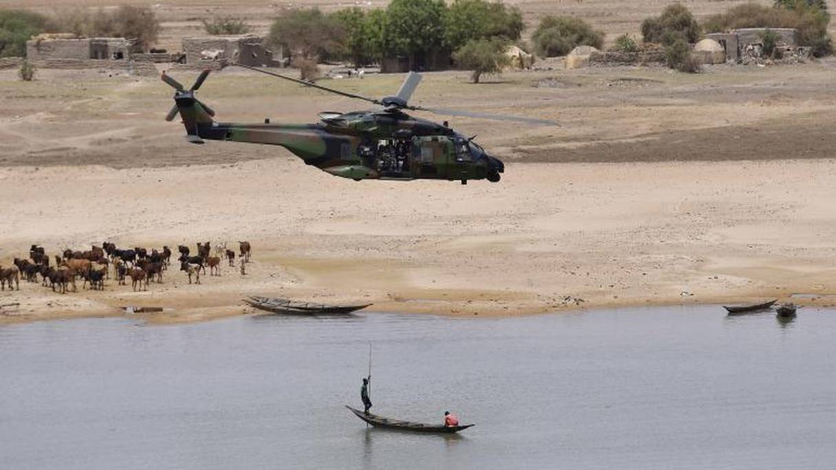 Un hélicoptère de la force Barkhane survolant une pirogue de pêcheur bonzo sur le fleuve Niger.
