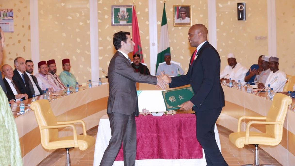 Mohamed Benchaâboun, PDG du groupe BCP et Tony Elumelu, PDG de Heirs Holdings, signant l'accord de partenariat devant le roi et le président nigérian.
