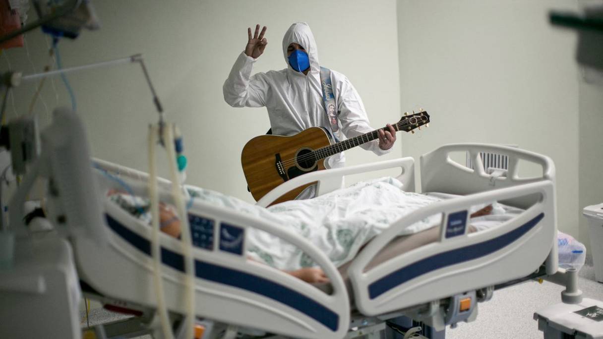 Un professionnel de la santé chante et prie pour un patient atteint du Covid-19, au service des soins intensifs de l'hôpital caritatif portugais de Belem, dans l'Etat de Para, au Brésil, lors des célébrations de Pâques, le 4 avril 2021.
