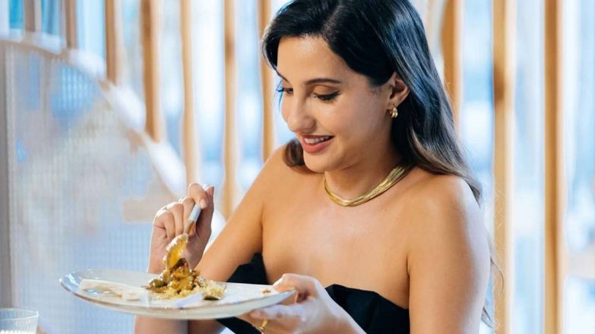 Nora Fatehi, invitée de l'émission Stars vs Food, déguste le poulet aux citrons confits et olives qu'elle vient de préparer. 
