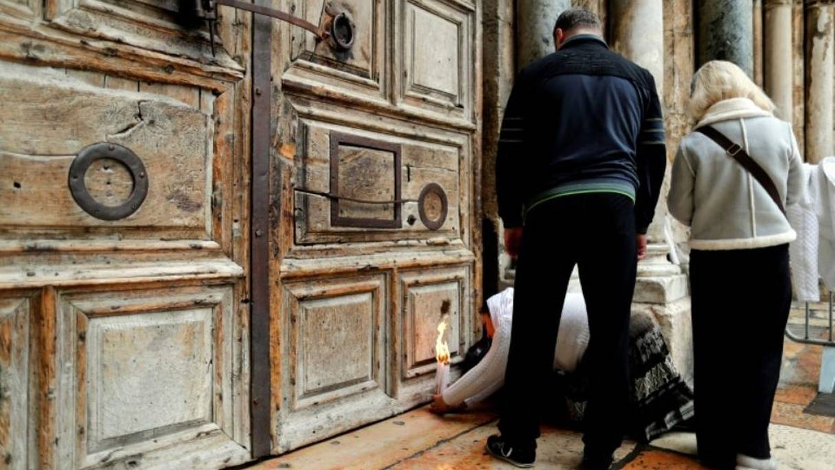 Une fidèle chrétienne allume une bougie aux portes, fermées, du Saint-Sépulcre à Jérusalem, le 26 février 2018. 
