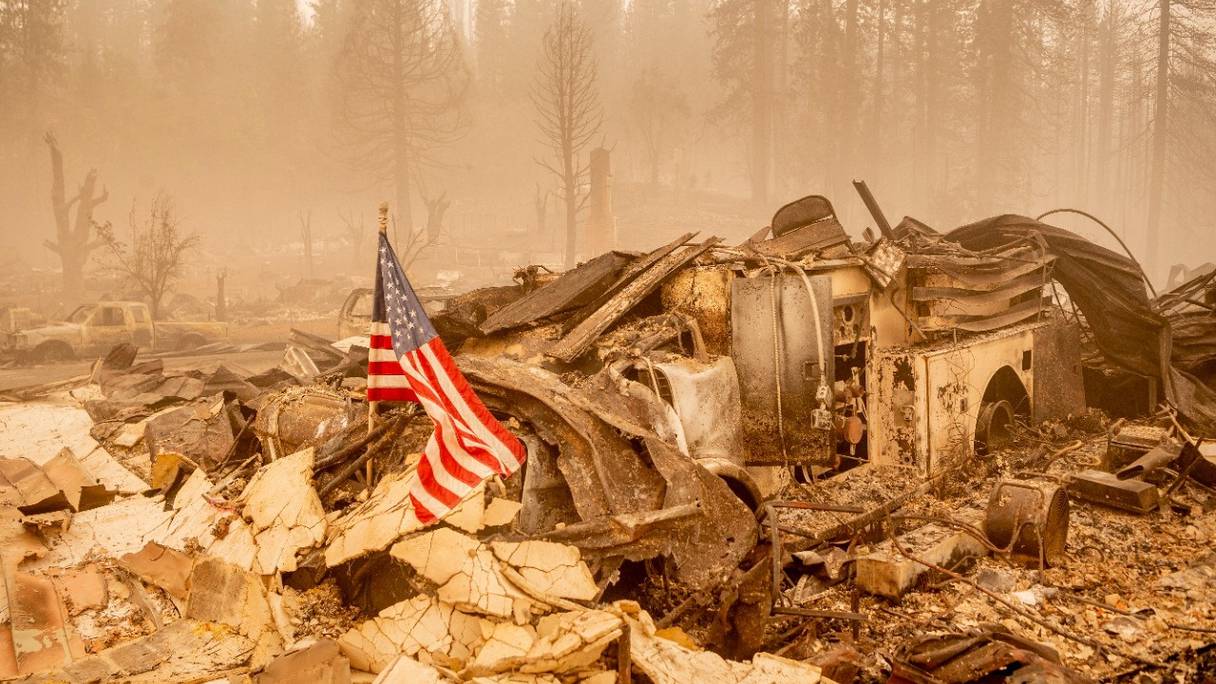 Un drapeau américain est placé sur un camion de pompiers calciné, dans le centre-ville de Greenville, en Californie, le 7 août 2021. Le Dixie Fire a ravagé 446 723 acres dans quatre comtés, une zone plus grande que Los Angeles.
