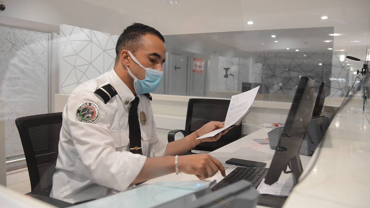 Un policier contrôle les documents sanitaires des voyageurs à l'aéroport Mohammed V de Casablanca, le 3 septembre 2021.
