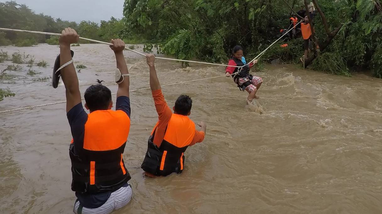 Des sauveteurs évacuent des résidents de leurs maisons près d'une rivière en crue en raison des fortes pluies provoquées par la tempête tropicale Kompasu, dans la ville de Gonzaga (province de Cagayan, au nord de Manille), le 11 octobre 2021.
