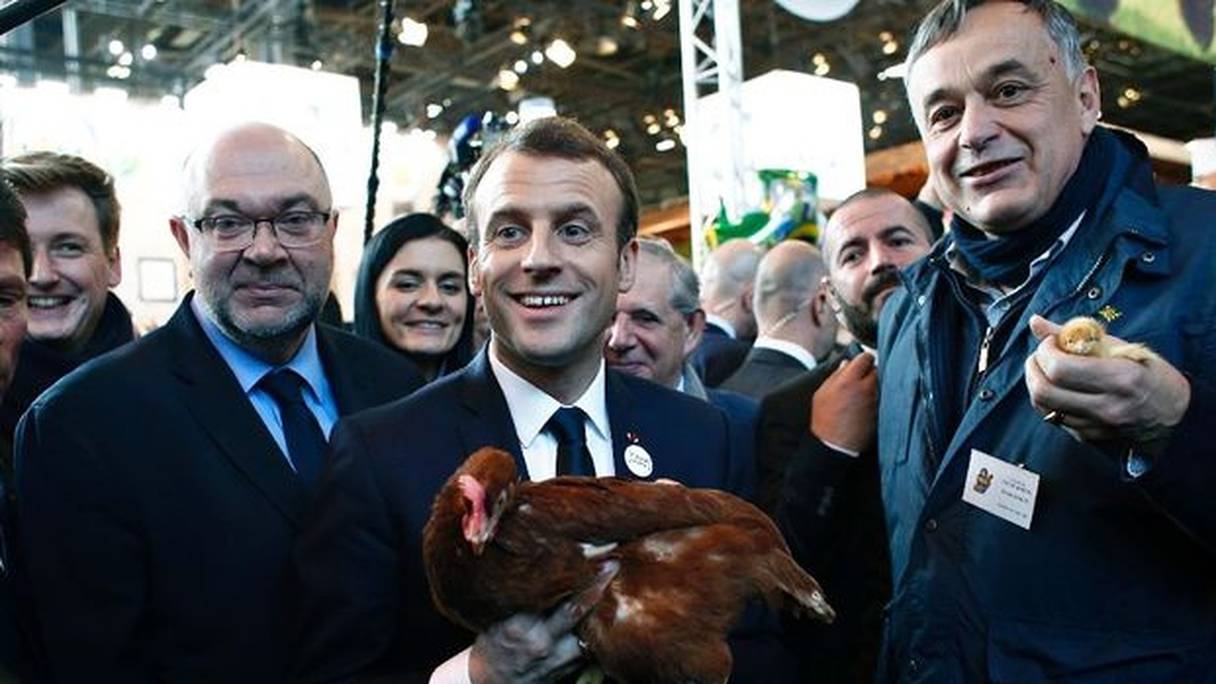 Emmanuel Macron tient une poule offerte par Yves de la Fouchardière (d) président des fermiers de Loué, au salon de l'agriculture le 24 février 2018. 
