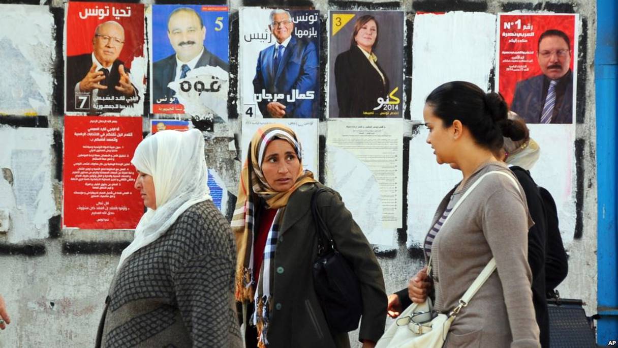 Des Tunisiennes devant un mur recouvert d'affiches de la campagne électorale, le 21 novembre 2014.
