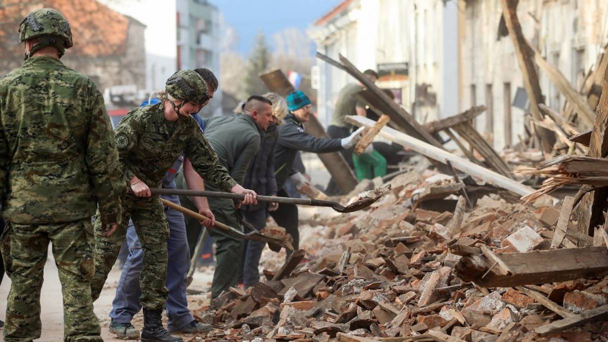 Des soldats croates et des habitants de Petrinja, à 50 km de Zagreb, déblaient les décombres le 29 décembre 2020. 
