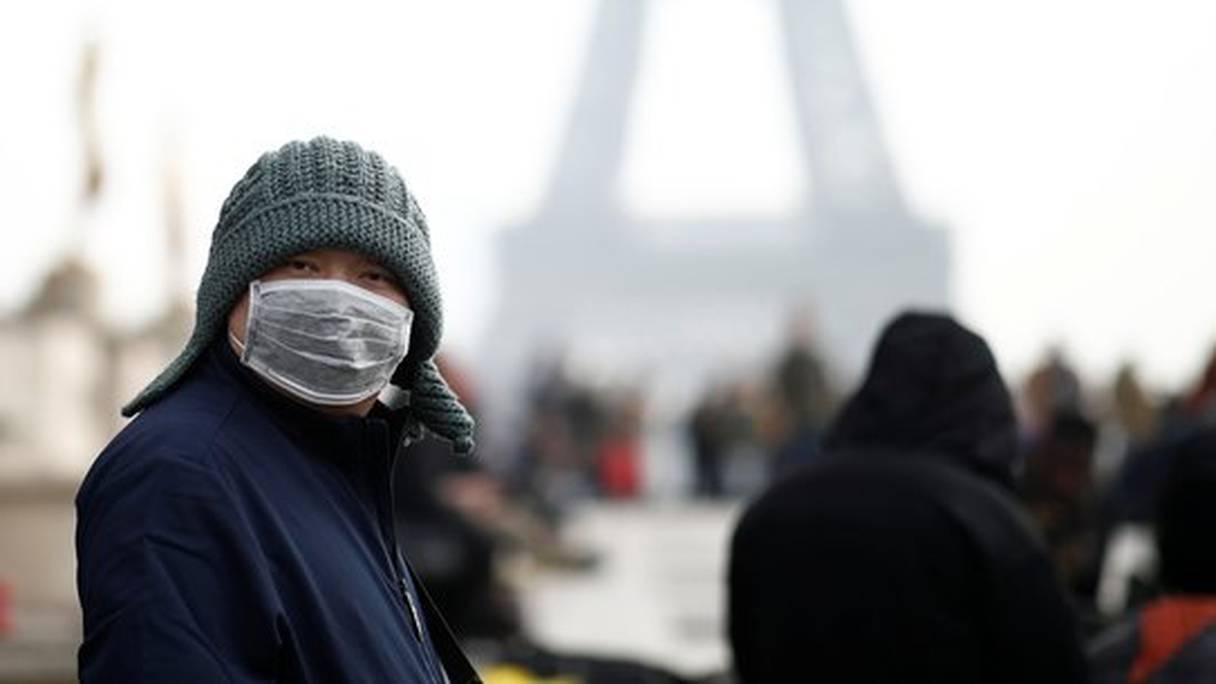 Une femme porte un masque de protection contre le Covid-19, au pied de la tour Eiffel, à Paris. 

