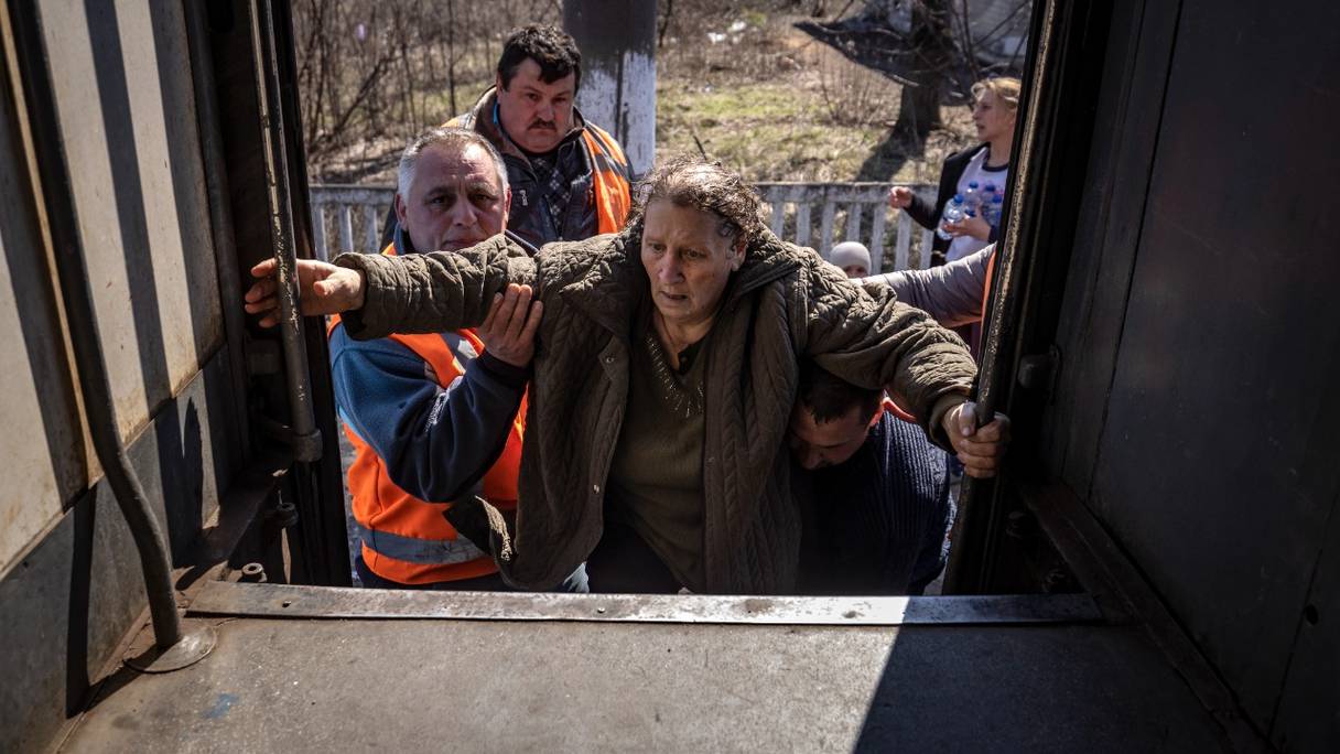 Une femme est aidée à monter à bord d'un train près de Severodonetsk, alors qu'elle fuit cette ville de la région du Donbass, le 7 avril 2022.
