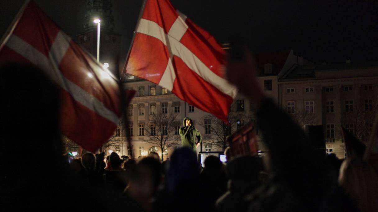 Le drapeau du Danemark est brandi par une foule de 1 000 à 1 200 personnes, qui se sont rassemblées lors d'une manifestation contre les nouvelles restrictions gouvernementales dues au Covid-19 à Copenhague, au Danemark, le 20 novembre 2021
