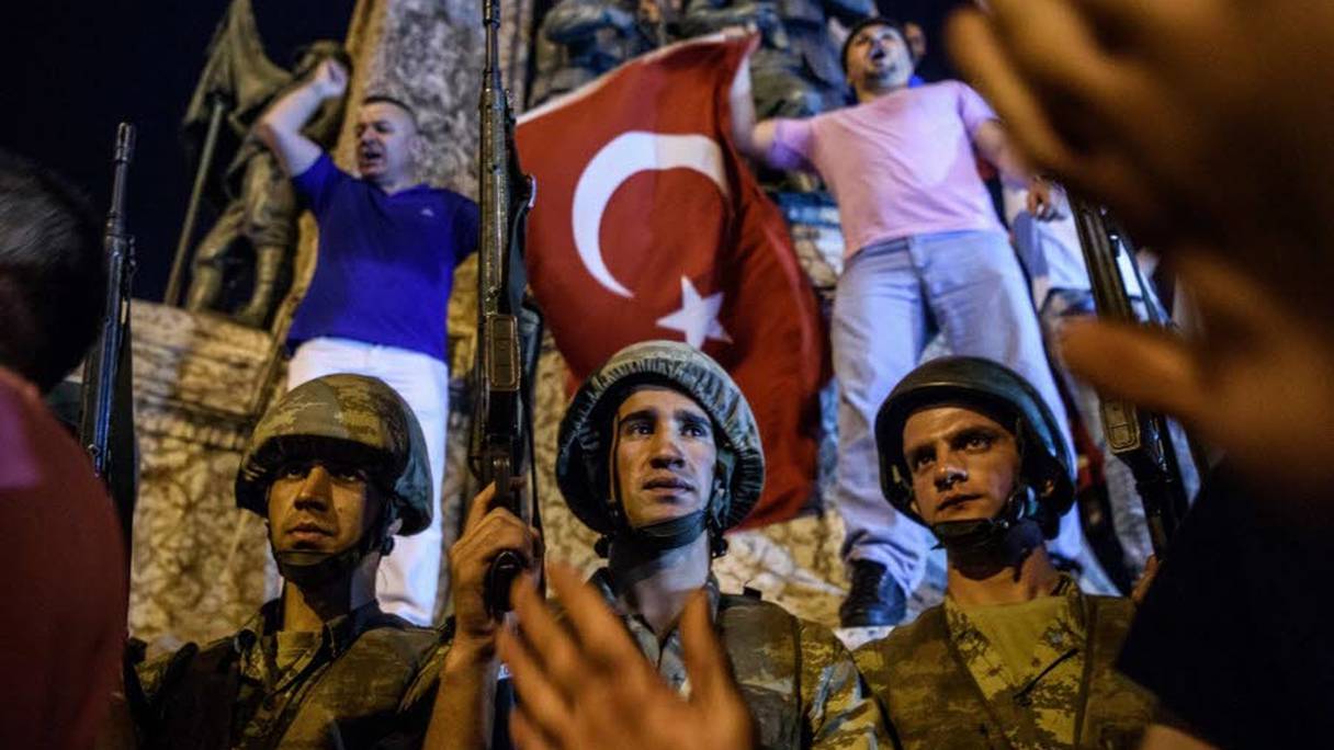 Des soldats turcs en armes sur la place Taksim alors que des personnes protestent contre la tentative de coup d'Etat, à Istanbul, le 16 juillet 2016.
