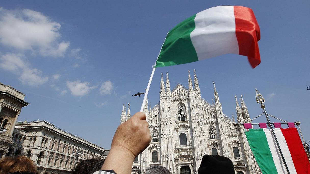 Un homme brandit un drapeau italien devant la cathédrale de Milan, en Italie.
