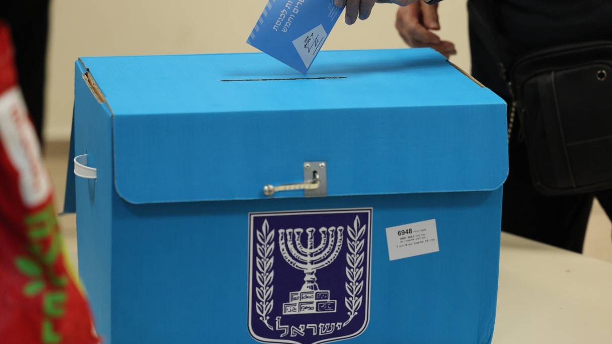 Un électeur israélien s'apprête à glisser son bulletin de vote dans une urne, au cours de la cinquième élection israélienne en moins de quatre ans, dans un bureau de vote de Tel Aviv, le 1er novembre 2022.
