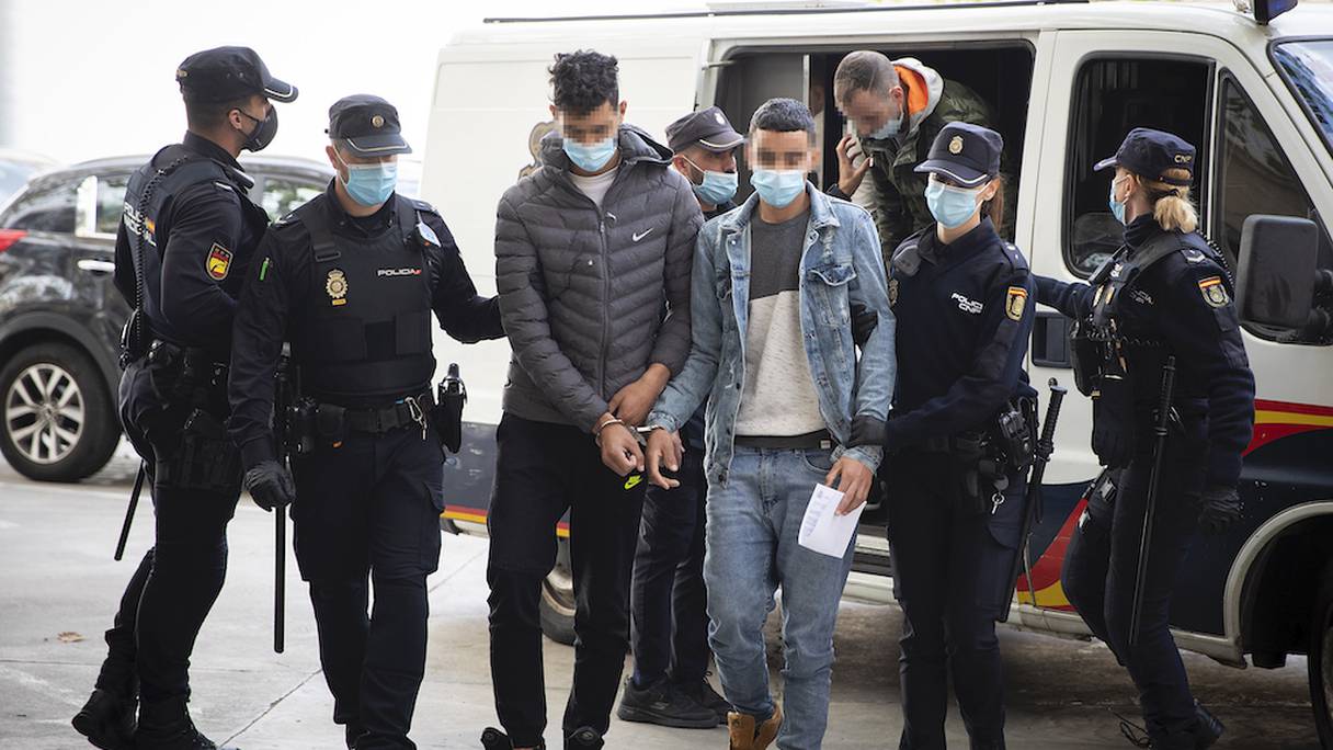 Deux Marocains, impliqués dans l’affaire d'une tentative d'émigration illégale depuis l'aéroport de Palma de Majorque, à bord d'un vol d'Air Arabia, sont escortés par des policiers au Palais de justice de Palma de Majorque, le 8 novembre 2021.
 
