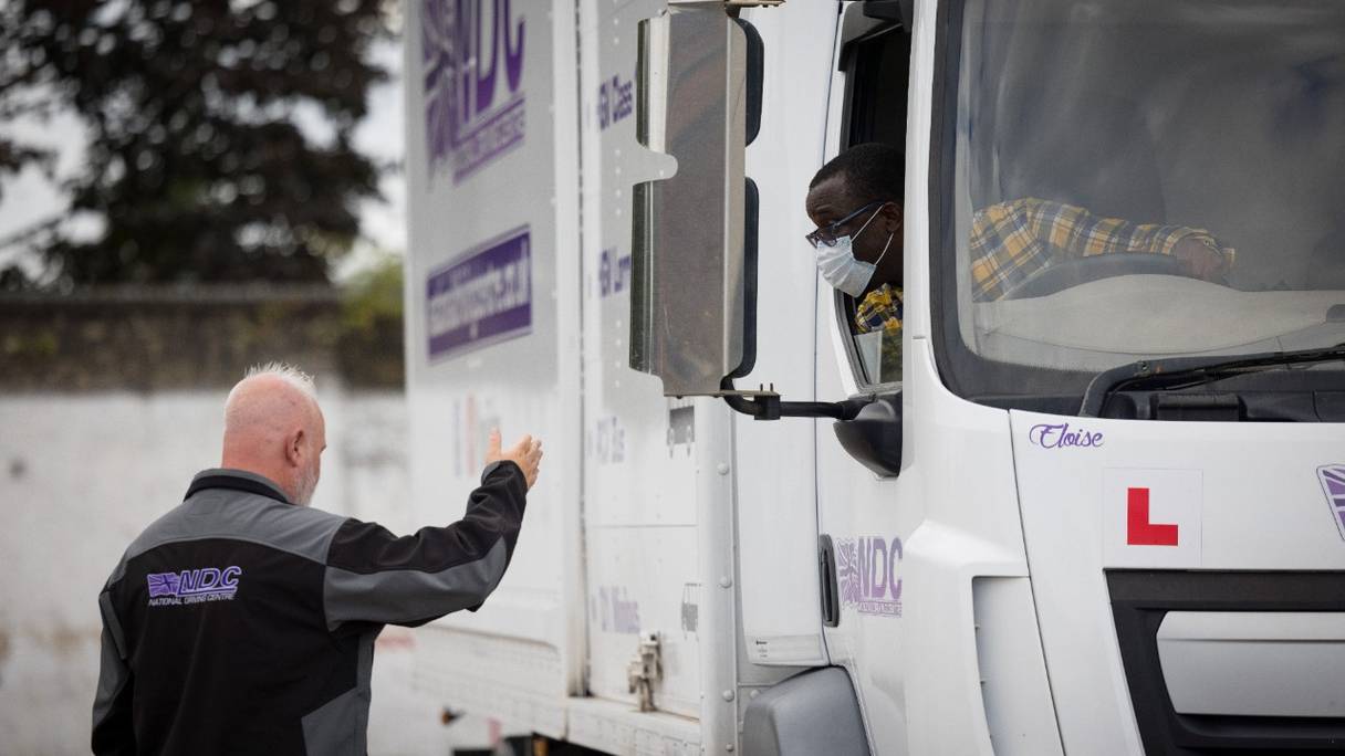 Un instructeur de conduite de poids lourds donne des instructions à un apprenti chauffeur de camion alors qu'il se prépare à faire reculer un camion au National Driving Centre à Croydon, dans le sud de Londres, le 1er octobre 2021.
