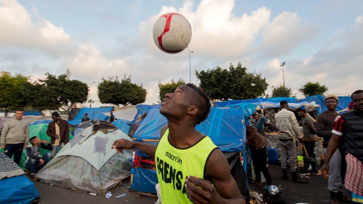 Un migrant subsaharien exerce ses talents sur un terrain de football de fortune, au milieu du camp de migrants à Ouled Ziane, à Casablanca, le 19 février 2018.
