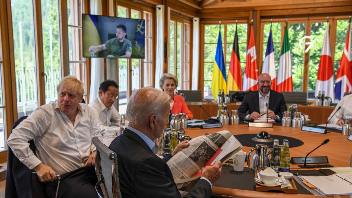 Joe Biden (au premier plan) lit un journal à une table ronde avec Boris Johnson, Fumio Kishida, Ursula von der Leyen et Charles Michel alors que le président ukrainien Volodymyr Zelensky s'adresse aux dirigeants du G7 par liaison vidéo, le 27 juin 2022 au château d'Elmau, dans le sud de l'Allemagne.
