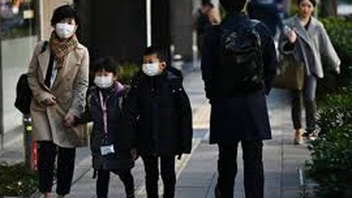 Mayumi Iijima se rend à son travail avec ses deux enfants, privés d'école pendant l'épidémie du Covid-19, le 6 mars 2020 à Tokyo. 
