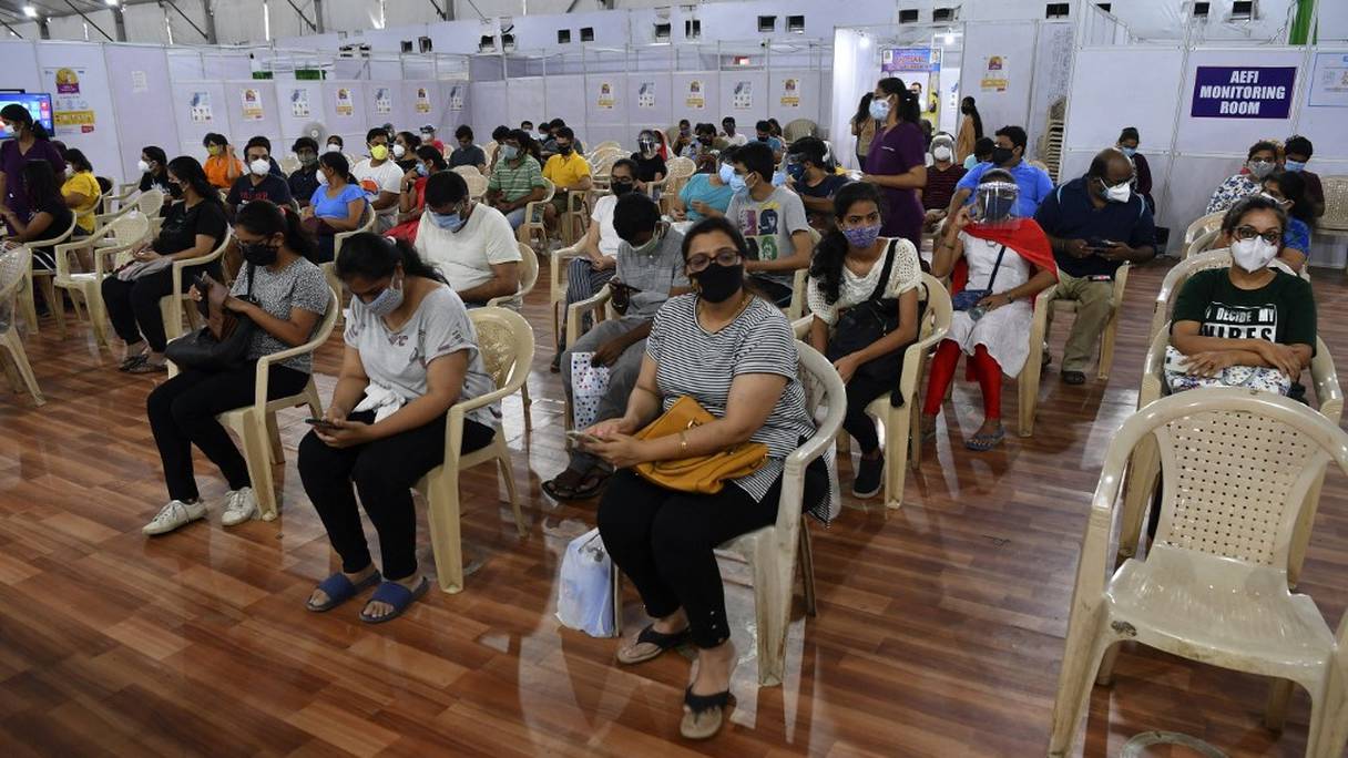 Des personnes sont assises dans une zone d'observation après avoir reçu une dose du vaccin Covishield d'AstraZeneca contre le Covid-19 dans le centre de vaccination BKC Jumbo à Bombay, le 2 mai 2021, au deuxième jour de la campagne de vaccination de l'Inde à tous les adultes.
