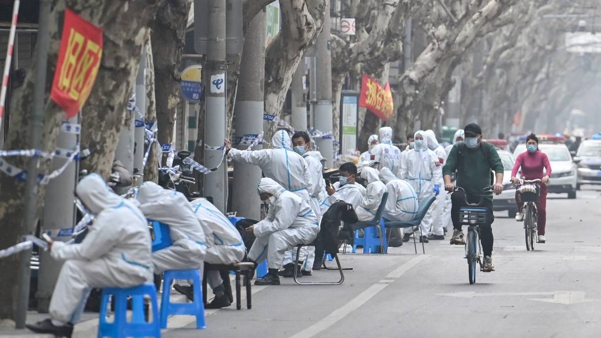 Des travailleurs en vêtements de protection à côté de certaines zones de confinement après la détection de nouveaux cas de Covid-19 à Shanghai, le 14 mars 2022.
