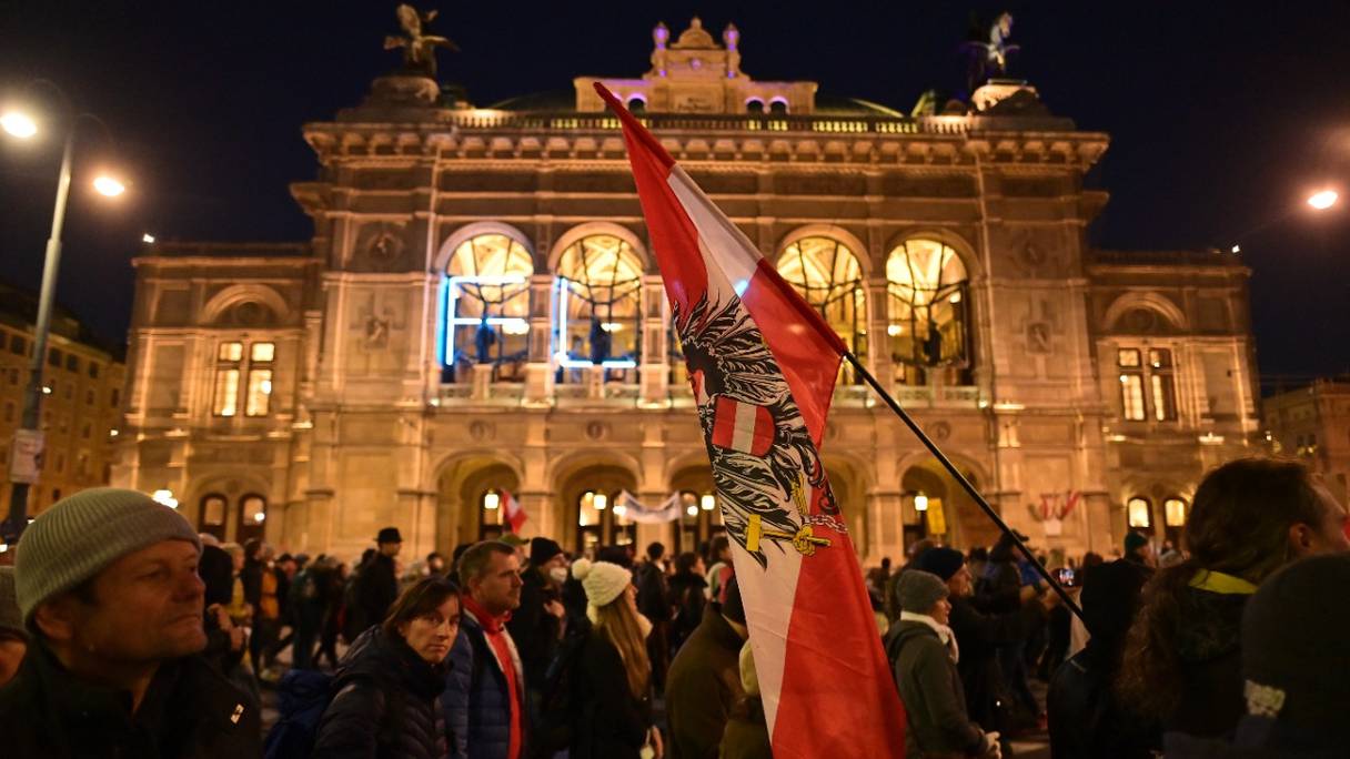 Des manifestants passent devant l'Opéra de Vienne, lors d'un rassemblement organisé par le parti d'extrême-droite autrichien FPOe contre les mesures prises pour lutter contre la pandémie de coronavirus (Covid-19), sur la place Maria Theresien Platz, en Autriche, le 20 novembre 2021.
