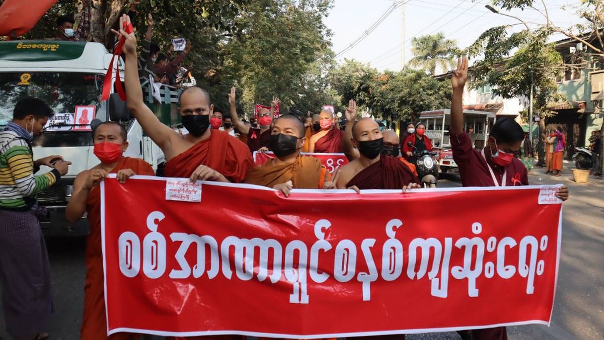 Des moines bouddhistes font un salut à trois doigts et exhibent une banderole où il est écrit "Que la dictature militaire tombe" lors d'une manifestation contre le coup d'Etat militaire à Mandalay, le 8 février 2021.
