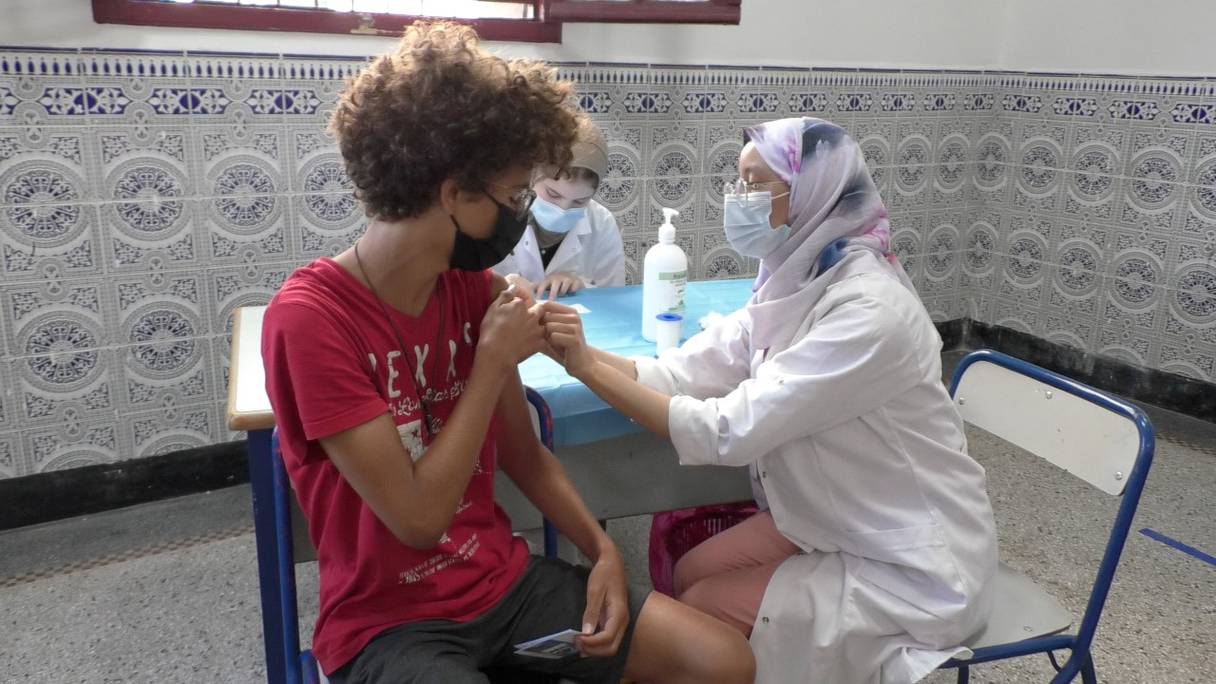 Une professionnelle de santé injecte une dose d'un vaccin anti-Covid-19 à un adolescent, au lycée Ibn Toumert à Casablanca. Le Maroc a débuté la vaccination des 12-17 ans, le 31 août 2021. 
